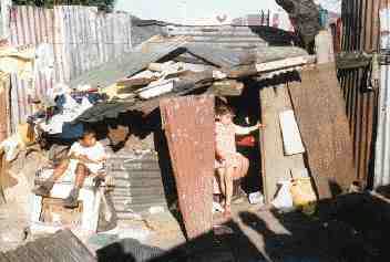 A girl looks out of her makeshift home in the squatter settlement south of Cape Town. Despite the wretched conditions, the residents in these areas have established social networks that are important to stability.