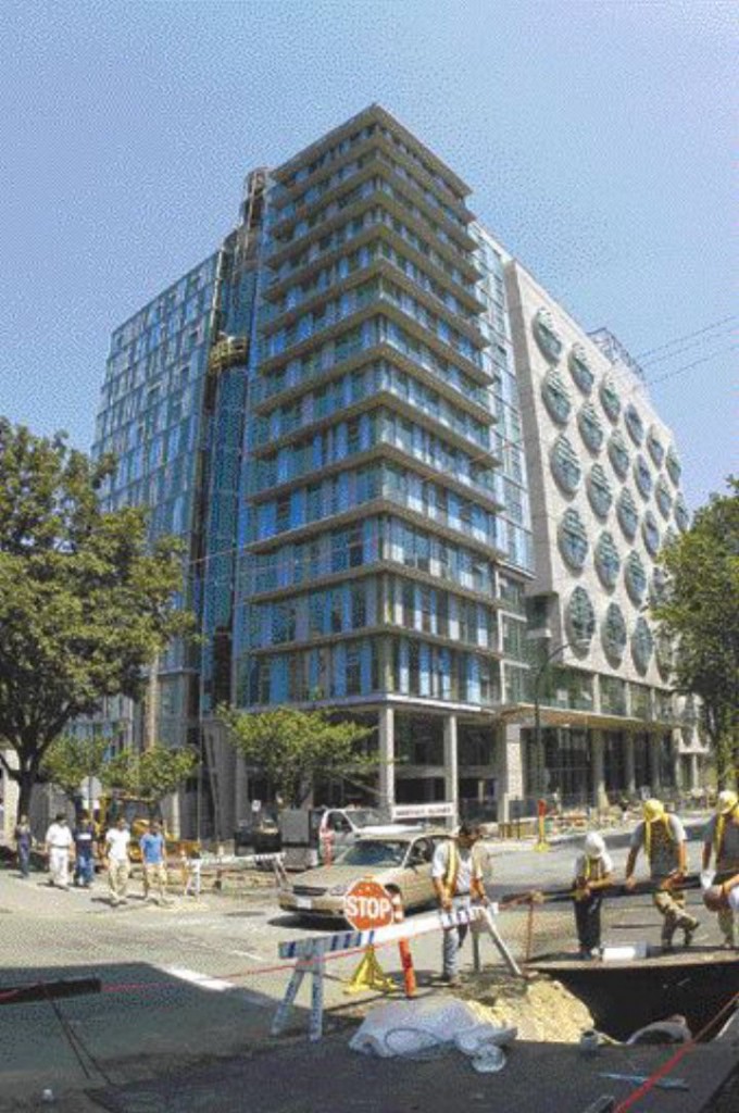 another construction view showing the building from 10th Avenue. The office wing is to the left and the laboratory wing with its circular "petri-dish" windows is to the right.